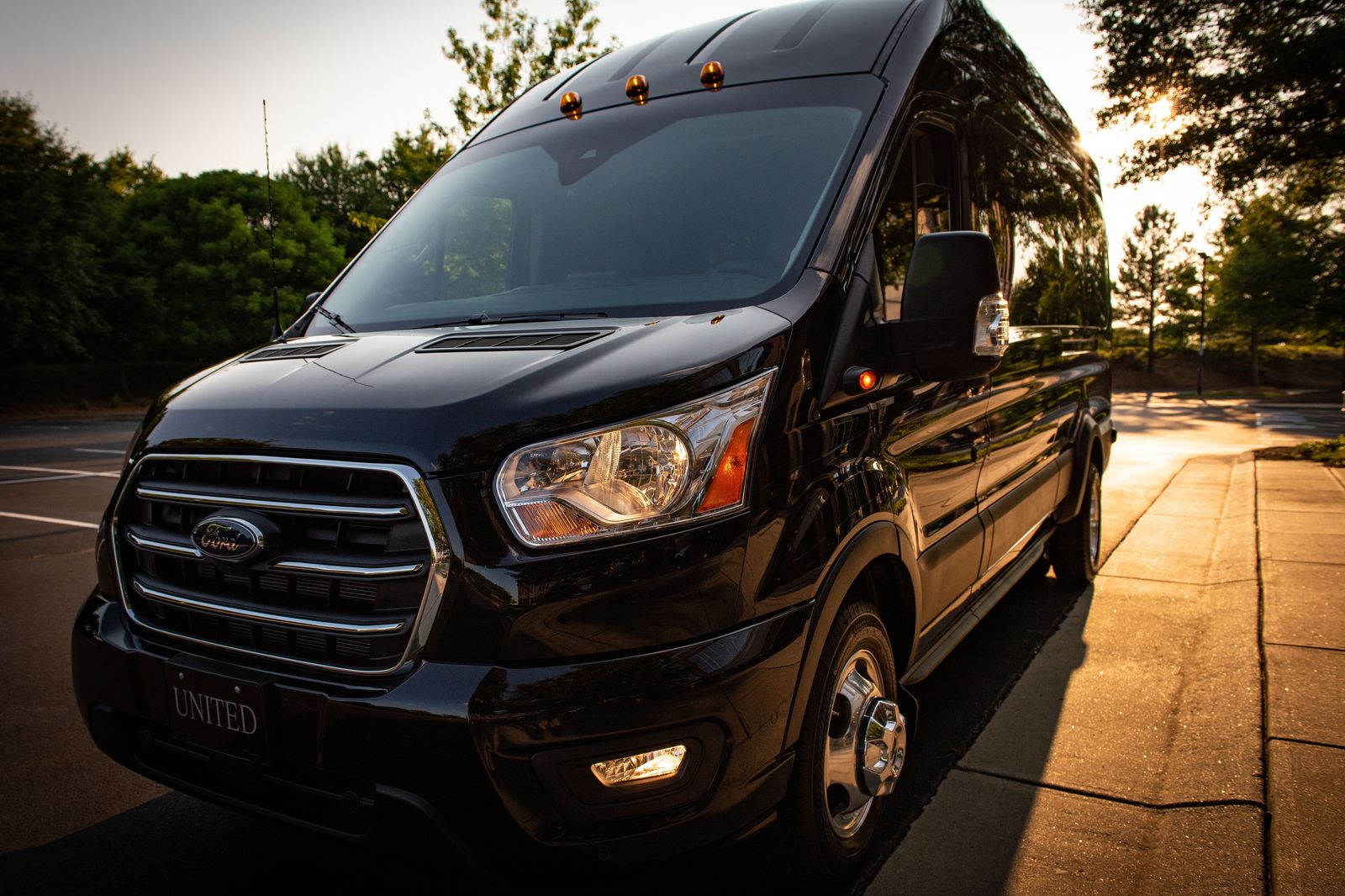 A black executive van outside a hotel at dusk