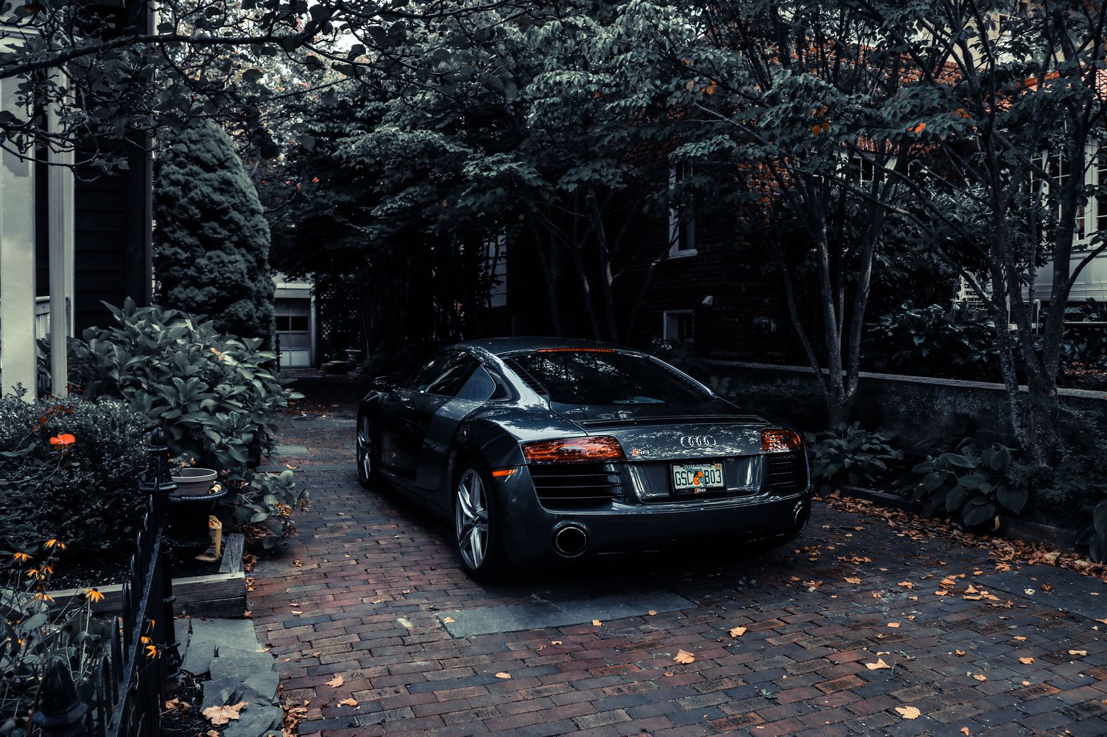 A chauffeur holding the rear door of a black sedan outside a Vaughan home at dawn
